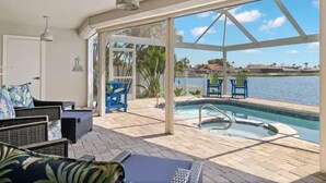 Ein Poolbereich mit Blick auf das Wasser, Gartenmöbel und eine überdachte Sitzgelegenheit.