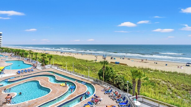 Un resort con amplia zona de piscina, acceso a la playa y vistas al océano.