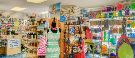Une boutique de souvenirs proposant divers articles, notamment des livres, des jouets et des sacs, présentés sur des étagères et des présentoirs.