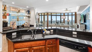 Una cocina moderna con una isla grande, lavavajillas integrado y vista al océano.