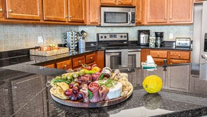 Una cocina con armarios de madera, microondas, estufa y un plato de fruta sobre la encimera.