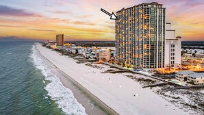Un hotel de gran altura con varias plantas, vista a la playa y un cielo al atardecer.