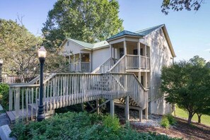 A two-story house with a porch and a wooden bridge leading to the entrance.