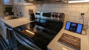 A modern kitchen with stainless steel appliances, a digital clock, and a welcome sign. - Perfect Northern Michigan Escape | Walkable TC Condo | Capri 212 (Traverse City)