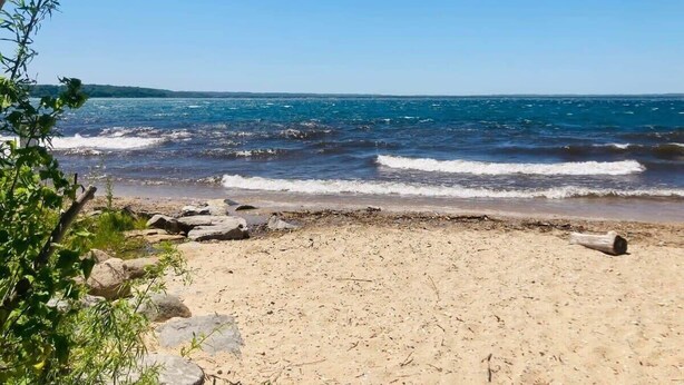 A beach with clear skies, waves, and a sandy shore. - Perfect Northern Michigan Escape | Walkable TC Condo | Capri 212 (Traverse City)