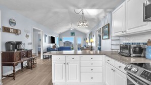 A spacious kitchen with white cabinetry, a large island, and modern appliances. - The Turtle Shell: Home Across from Ocean Crest Pier and Restaurant (Oak Island)