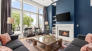 Een moderne woonkamer met een open haard, comfortabele zithoek en een groot raam met uitzicht op de omgeving.