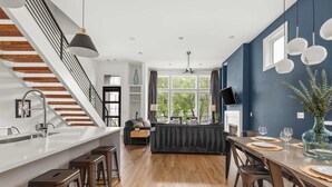 Een moderne keuken met een centraal eiland, houten vloer en een trap met een zwarte balustrade.