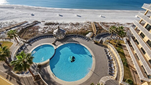 A resort with a large pool area, a beach view, and a building with balconies.