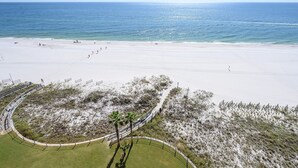 A beach with a sandy shore, a few people, and a clear view of the ocean.