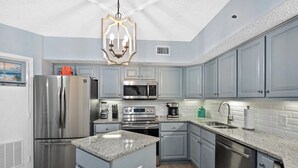 A modern kitchen with grey cabinets, stainless steel appliances, and a granite countertop.