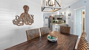 A dining area with a wooden table, woven chairs, and a decorative wall piece.