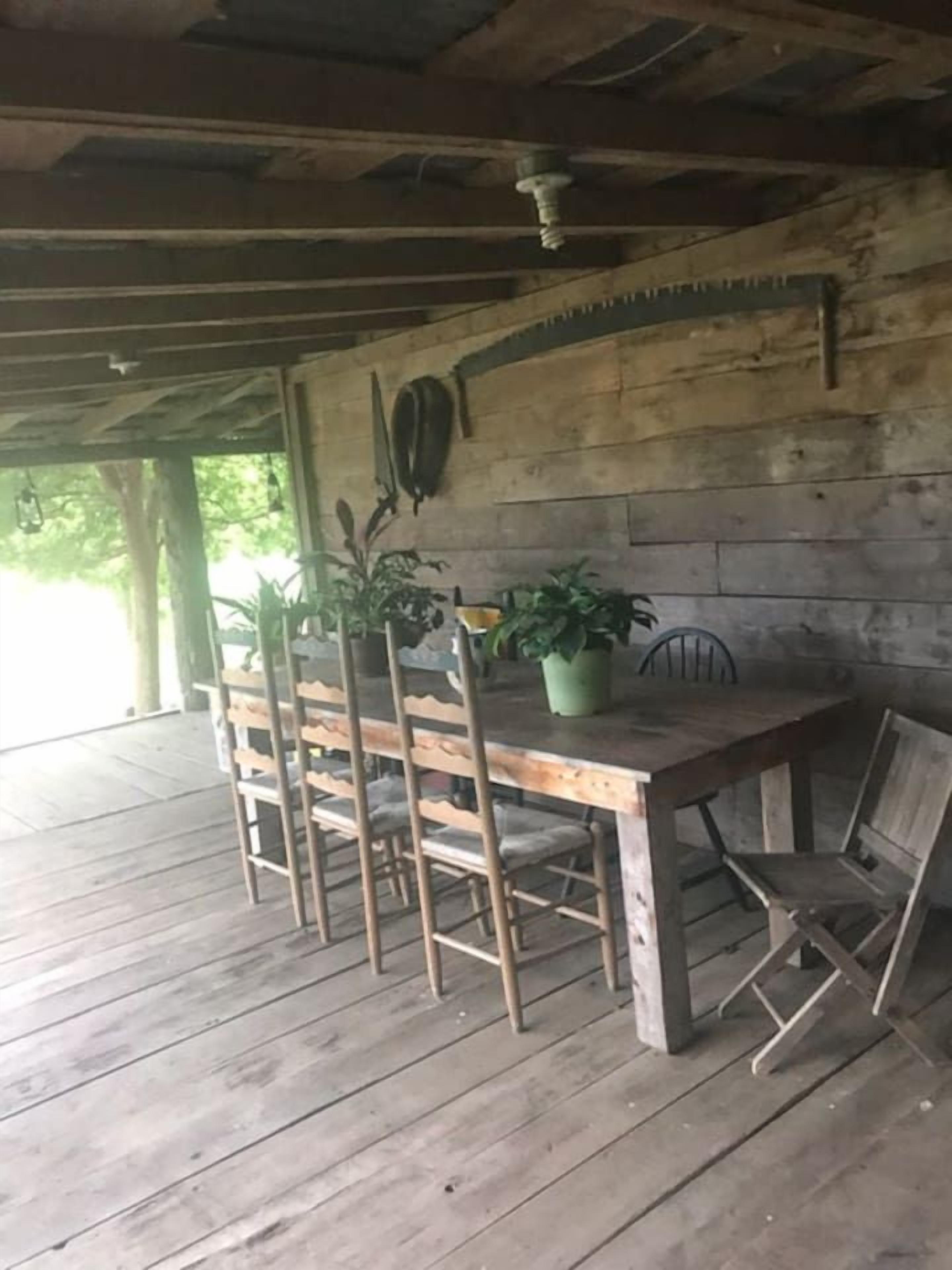 A rustic wooden table and chairs under a wooden ceiling with exposed beams.