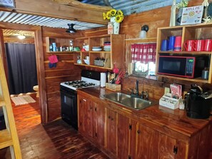 Una cocina con armarios de madera, estufa, pileta y microondas.