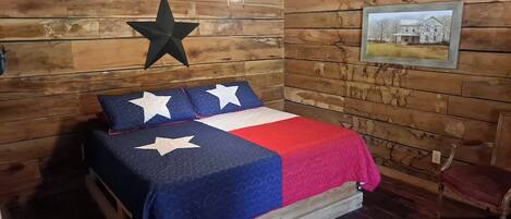 A room with a bed, star-shaped wall decoration, a framed picture, and a chair.