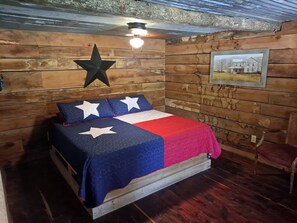 Una habitación con una cama, decoración en la pared con forma de estrella, un cuadro enmarcado y una silla.