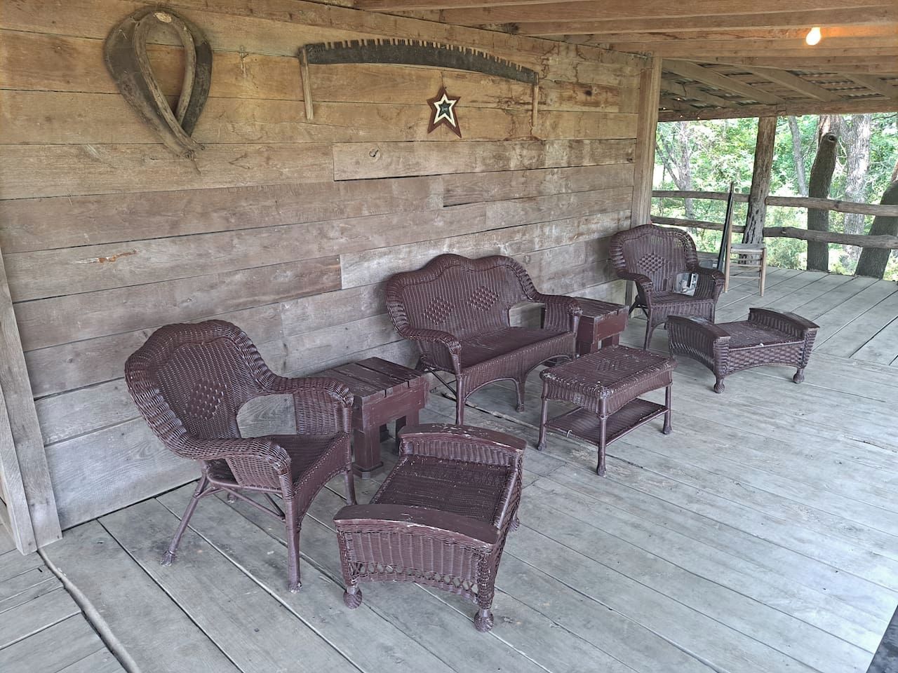 A covered outdoor seating area with wicker furniture and a star decoration on the wall.