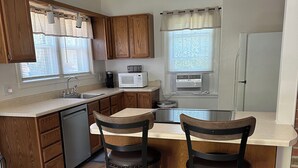 A modern kitchen with wooden cabinets, a built-in microwave, and a refrigerator. There are two stools at the island and a sink with a faucet. - Relax, unwind and enjoy!  (Cody)