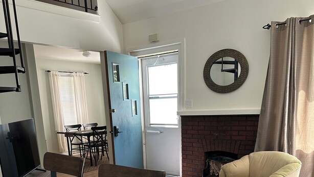 A spacious living room with a fireplace, a dining area with a table and chairs, and a staircase leading to an upper level. - Relax, unwind and enjoy!  (Cody)