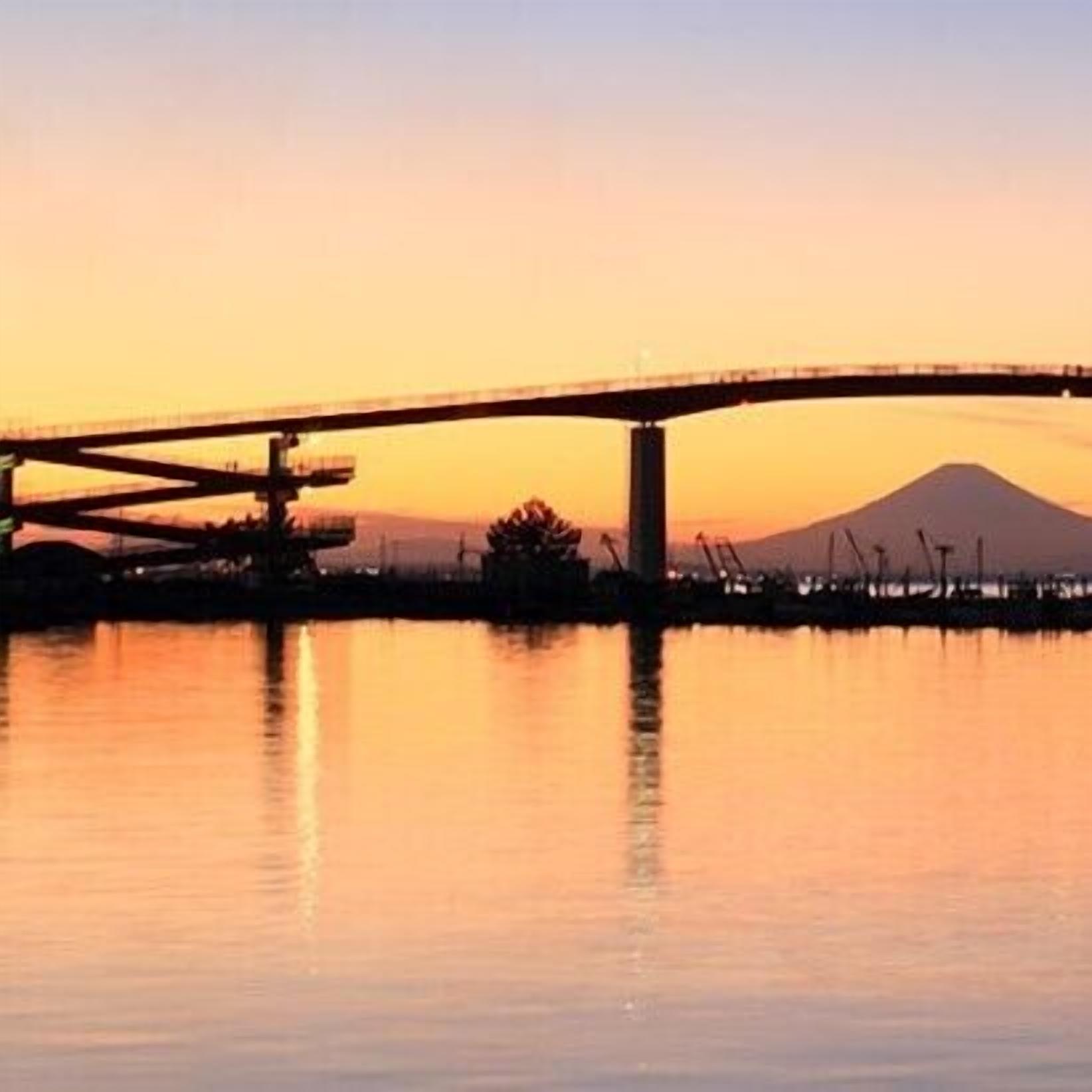 A bridge over water with a mountain in the background.