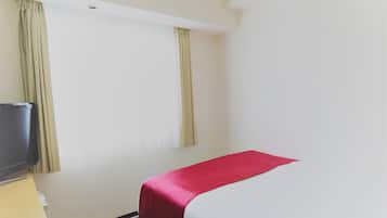 Een hotelkamer met een bed, een televisie op een standaard en gordijnen voor de ramen.