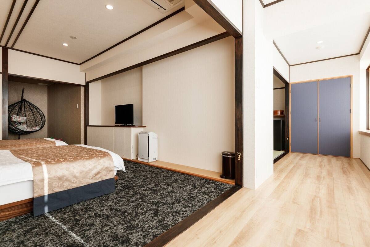Una habitación de hotel moderna con una cama grande, una silla colgante, un televisor y un armario.