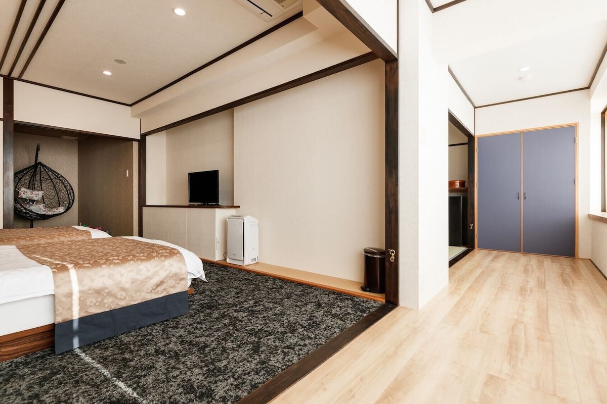 Moderni hotellihuone, jossa on suuri sänky, riipputuoli, televisio ja vaatekaappi.