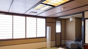 A tatami mat room with a low table and cushions, a sliding door, and a sofa in the background. - Aiken to Sugosu Honkaku Ryokan Gekka (Awara)