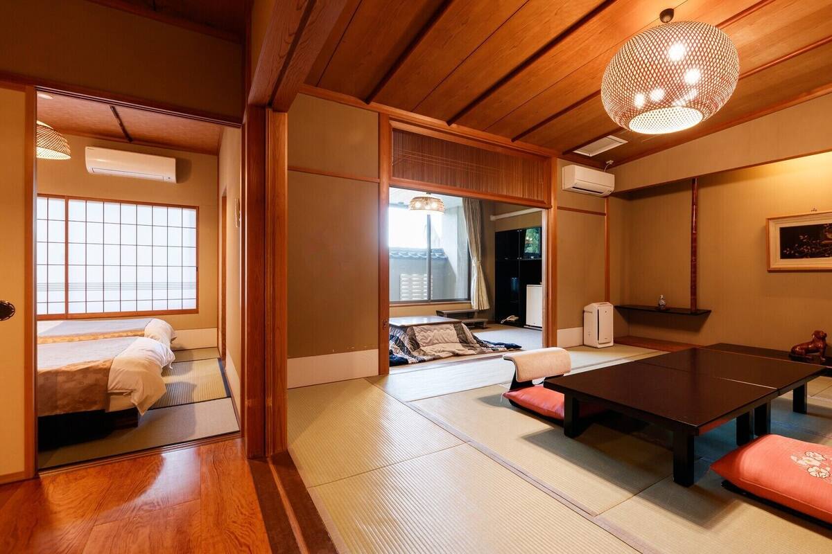Una habitación japonesa tradicional con suelo de tatami, una mesa baja, cojines e una lámpara colgante.