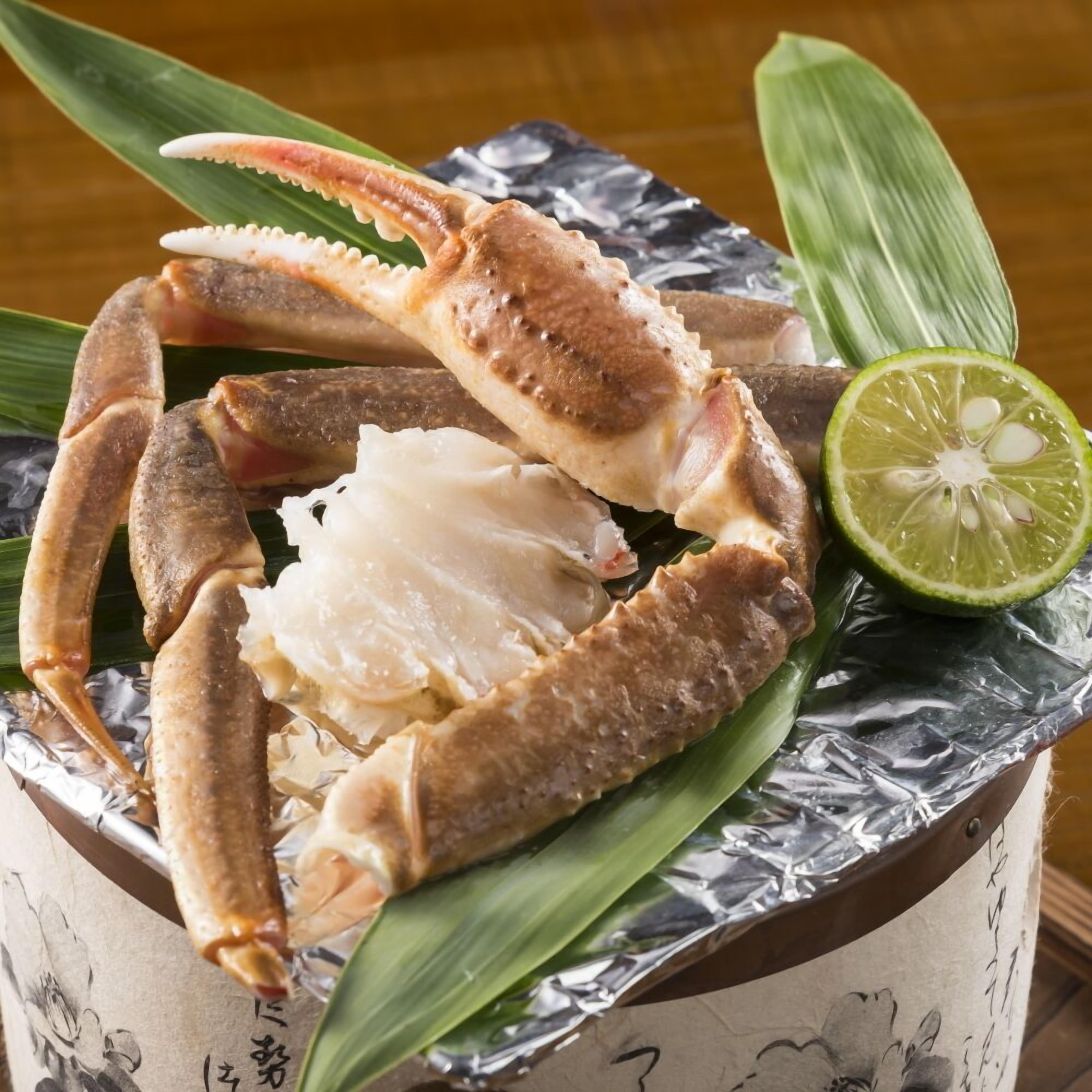 A crab on a leaf with foil and a lime wedge.