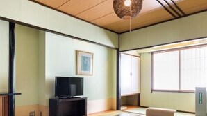 A traditional Japanese room with tatami flooring, a television, a sofa, and a table. - Aiken to Sugosu Honkaku Ryokan Gekka (Awara)