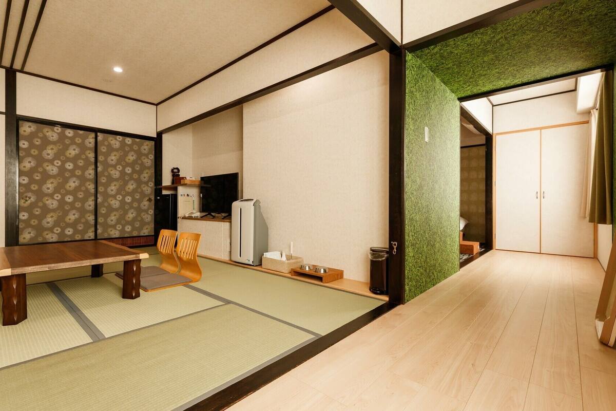 Una habitación de estilo japonés tradicional con suelo de tatami, una mesa baja y una puerta corredera.