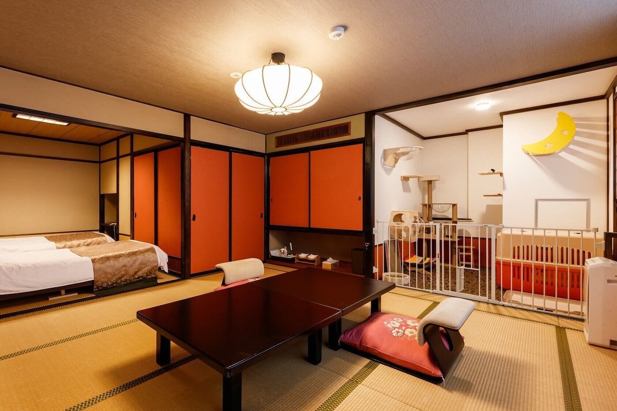 Perinteinen japanilaistyylinen huone, jossa on tatamimatto, matala pöytä, kaksi sänkyä ja liukuvat ovet.