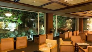 A hotel lobby with wicker furniture, a large chandelier, and a view of greenery outside. - Aiken to Sugosu Honkaku Ryokan Gekka (Awara)
