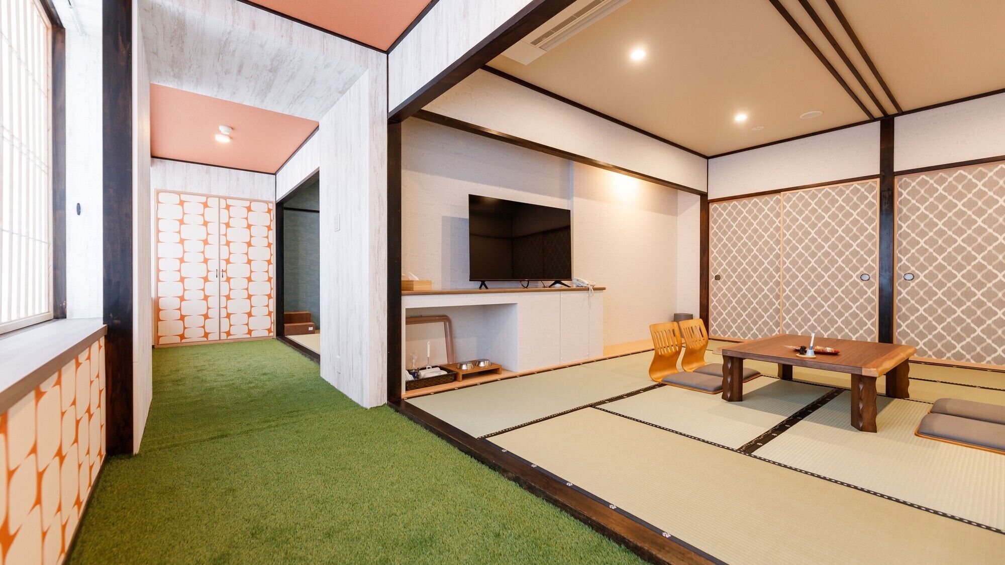 A traditional Japanese room with tatami flooring, a television, and a low table with cushions.