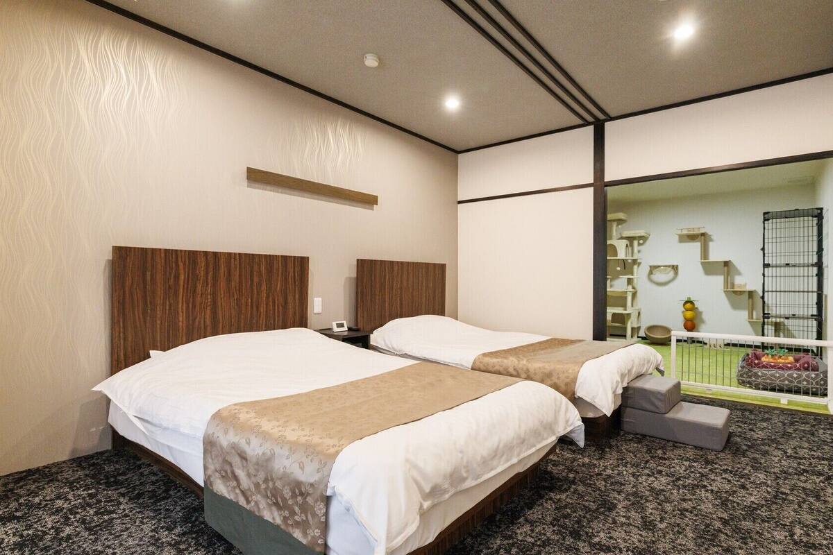 Habitación de hotel con dos camas, un espejo grande, zona para mascotas y vistas al exterior.