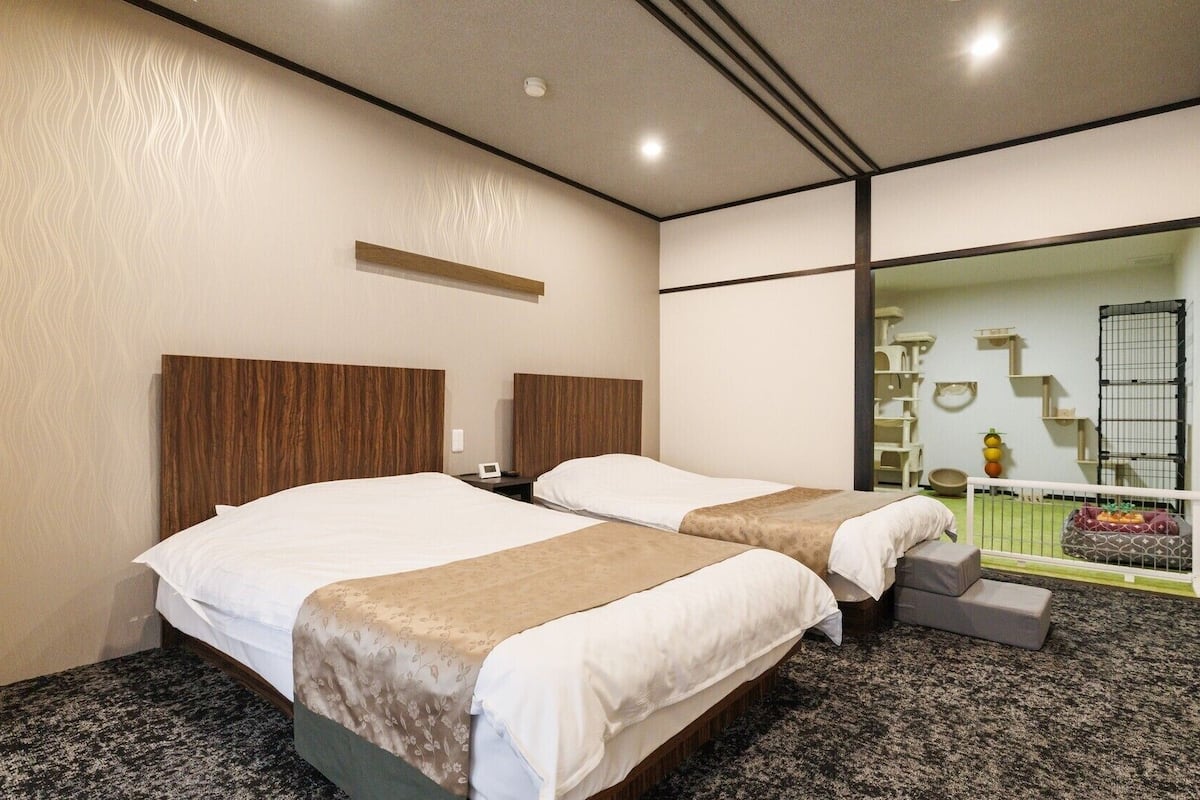 Hotellihuone, jossa on kaksi sänkyä, suuri peili, lemmikkialue ja näkymä ulos.