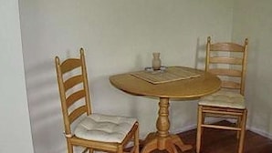 A small dining area with a round wooden table and two wooden chairs with cushioned seats. - Linden Homestead: King Bed Cottage on Century Farm Property (Stanley Bridge)