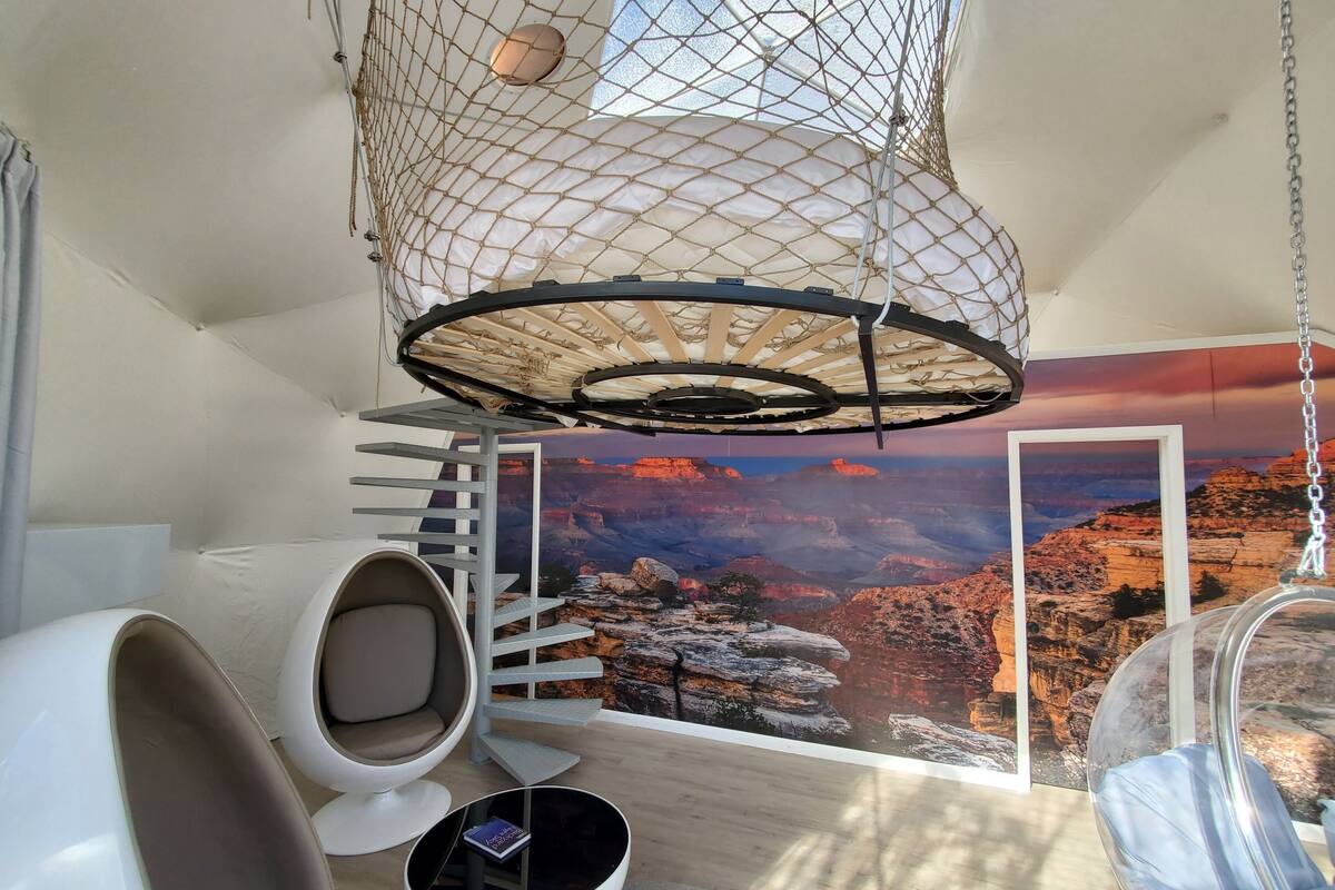 Une pièce dotée d’un fauteuil suspendu, d’une balançoire, d’un escalier en colimaçon et d’une grande fresque représentant un canyon.