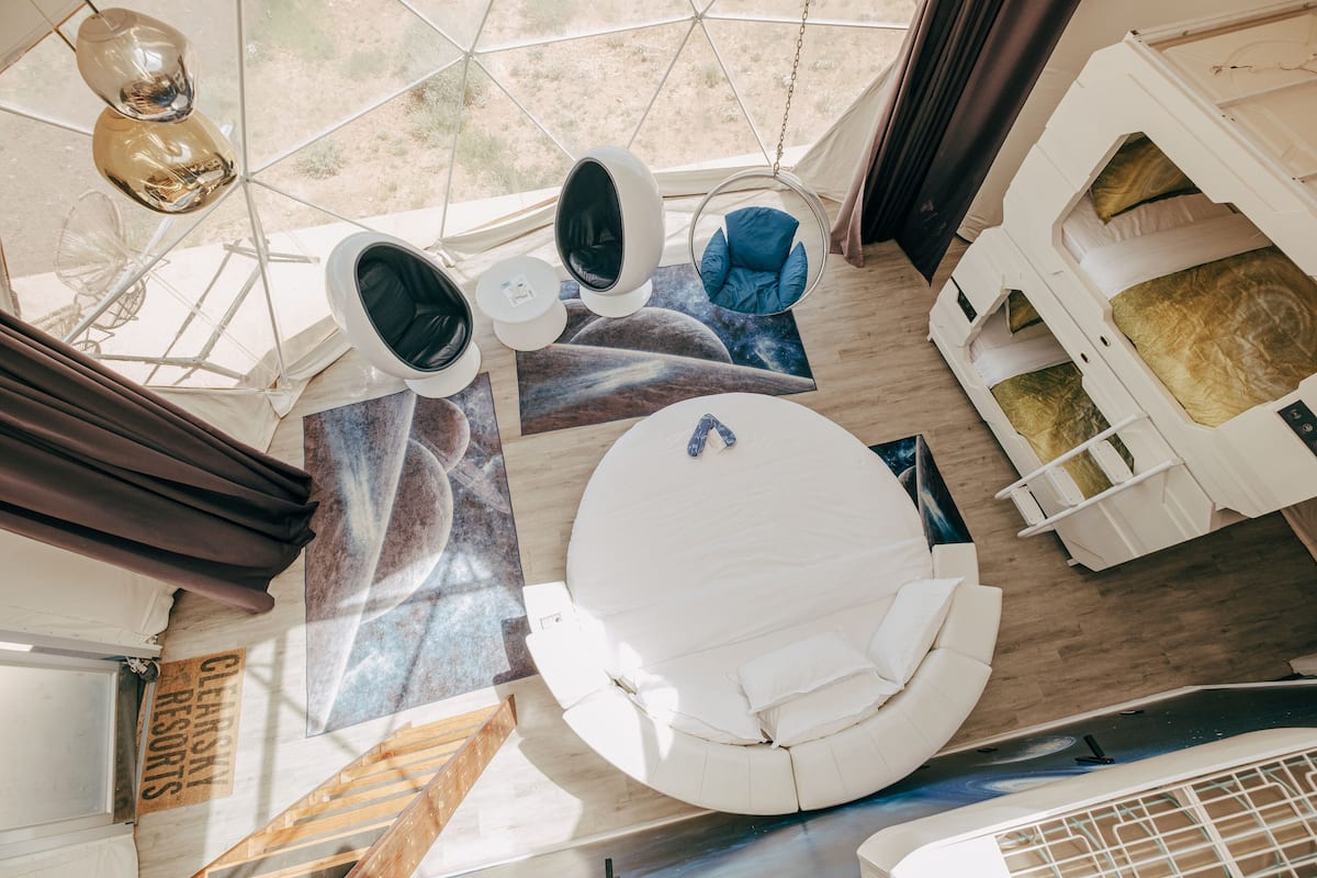 Une pièce moderne et circulaire, avec un canapé blanc, un fauteuil suspendu et une petite table.