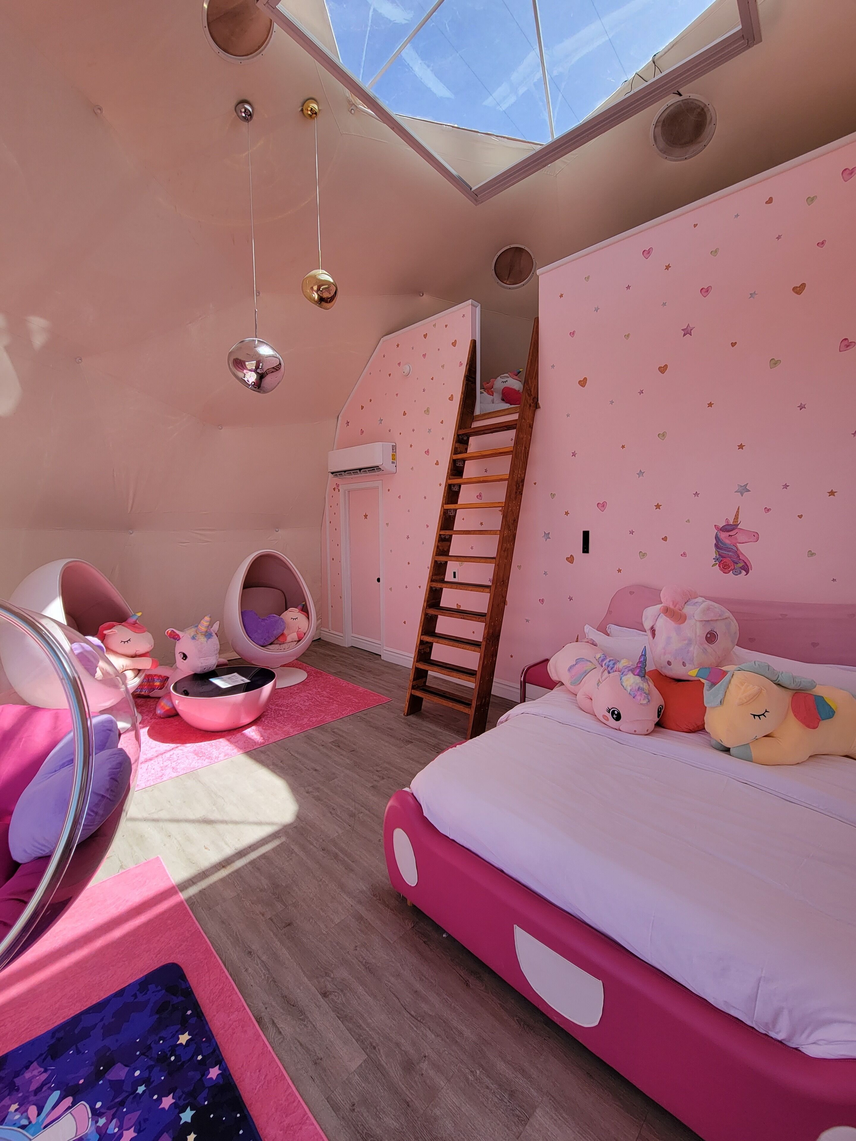 Un dormitorio decorado en tonos rosas con una litera, una escalera y un tragaluz.
