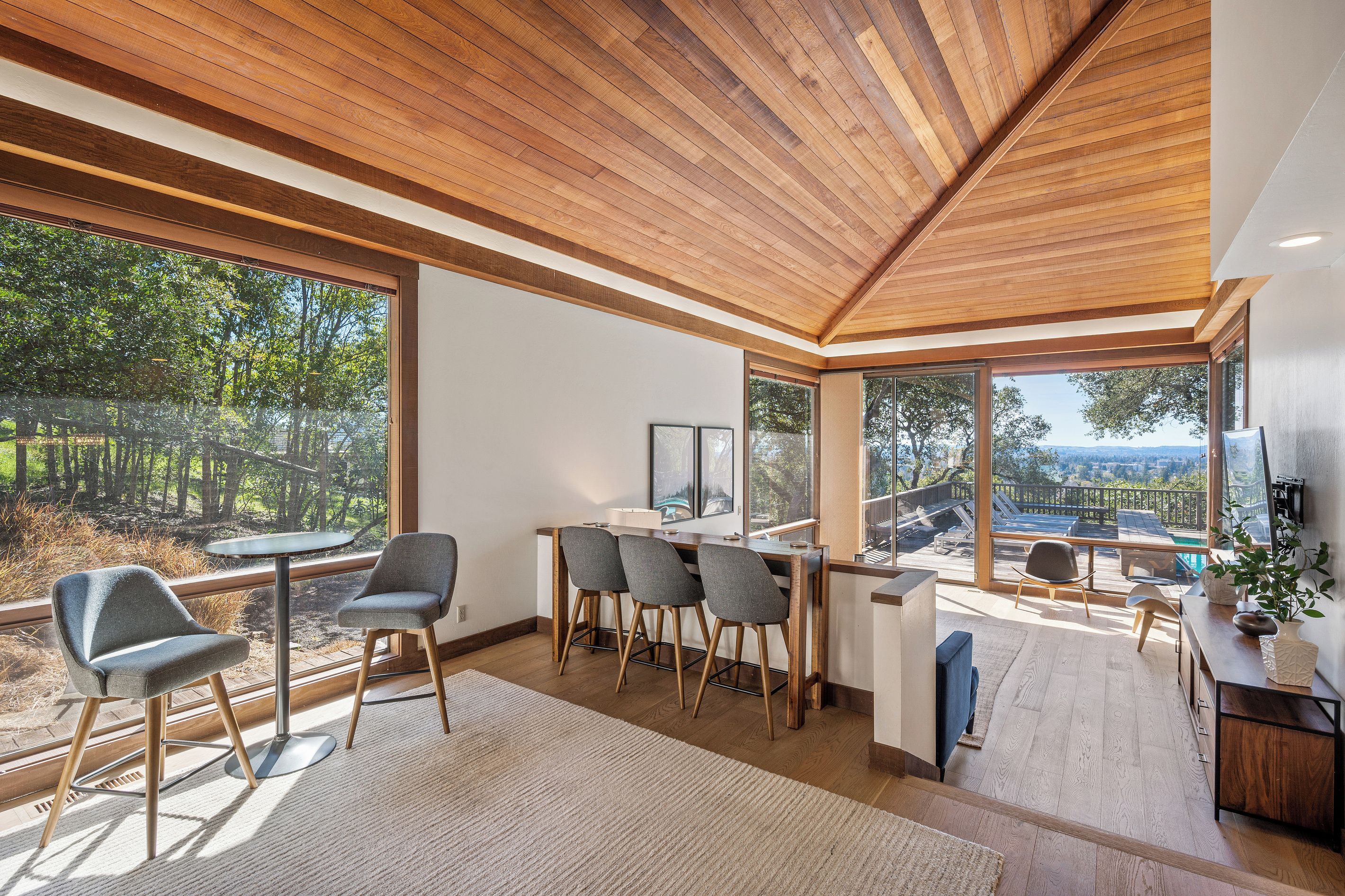 A modern interior with a dining area, large windows, and a view of the outdoors.