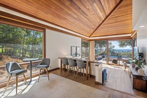 A modern interior with a dining area, large windows, and a view of the outdoors. - Haven: 5 King Bedrooms, Heated Pool and Hot Tub (Santa Rosa)