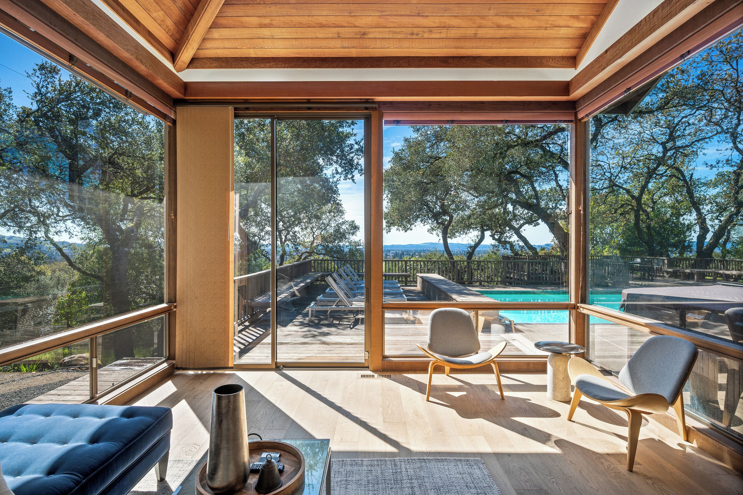 A modern outdoor deck with a pool, lounge chairs, and a view of the surrounding landscape.
