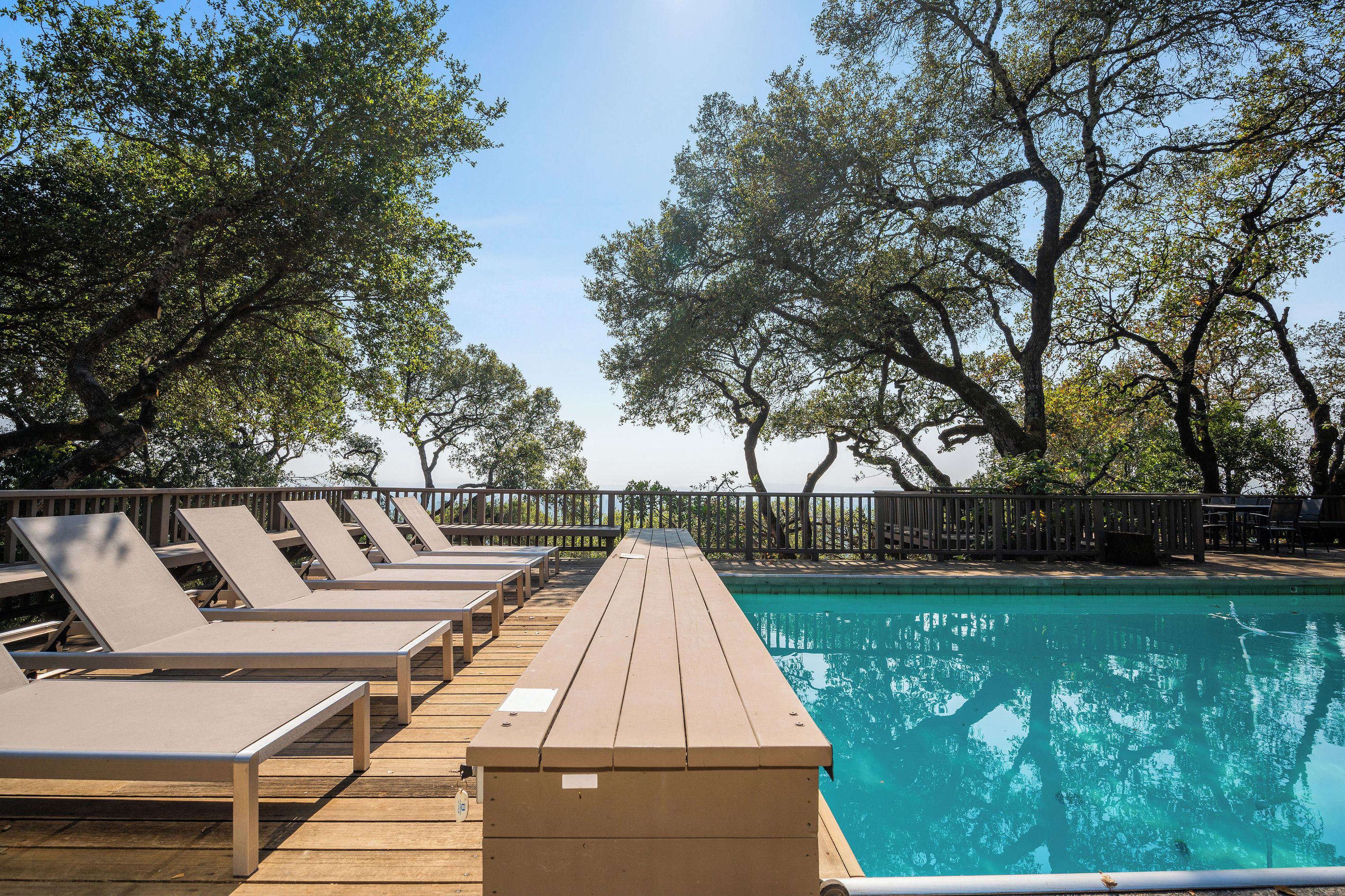 Zona junto a la piscina con sillones de descanso y terraza de madera.