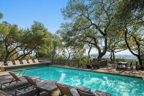 A swimming pool with lounge chairs and a table, surrounded by trees and a view of the landscape. - Haven: 5 King Bedrooms, Heated Pool and Hot Tub (Santa Rosa)