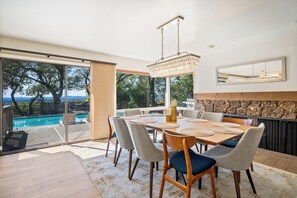 A dining area with a pool view, a chandelier, and a stone accent wall. - Haven: 5 King Bedrooms, Heated Pool and Hot Tub (Santa Rosa)