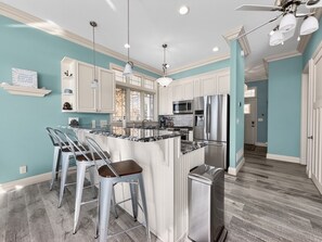 A modern kitchen with white cabinetry, stainless steel appliances, and a central island with bar stools.