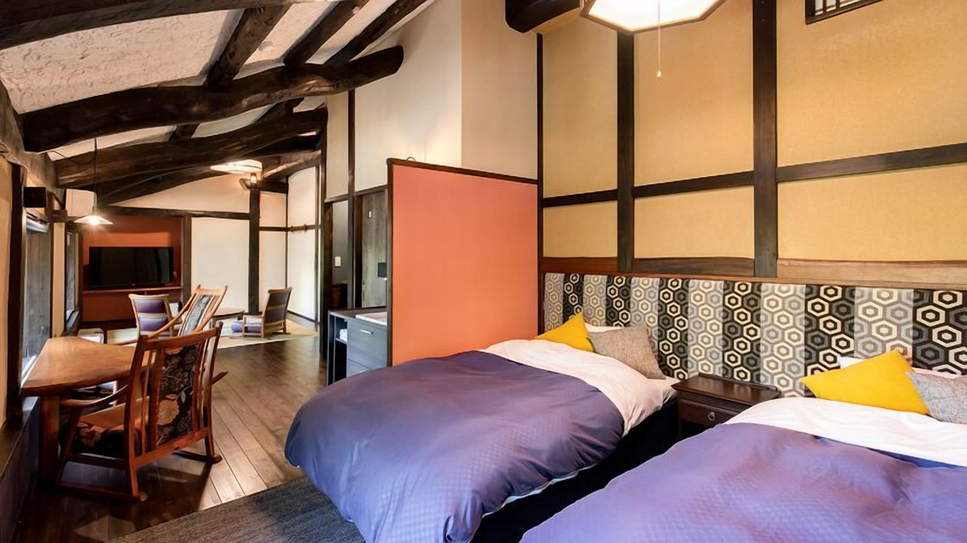 Ein Hotelzimmer mit zwei Betten, einem Schreibtisch und einem Fernseher.