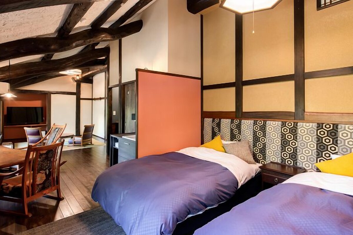 A hotel room with two beds, a desk, and a television.